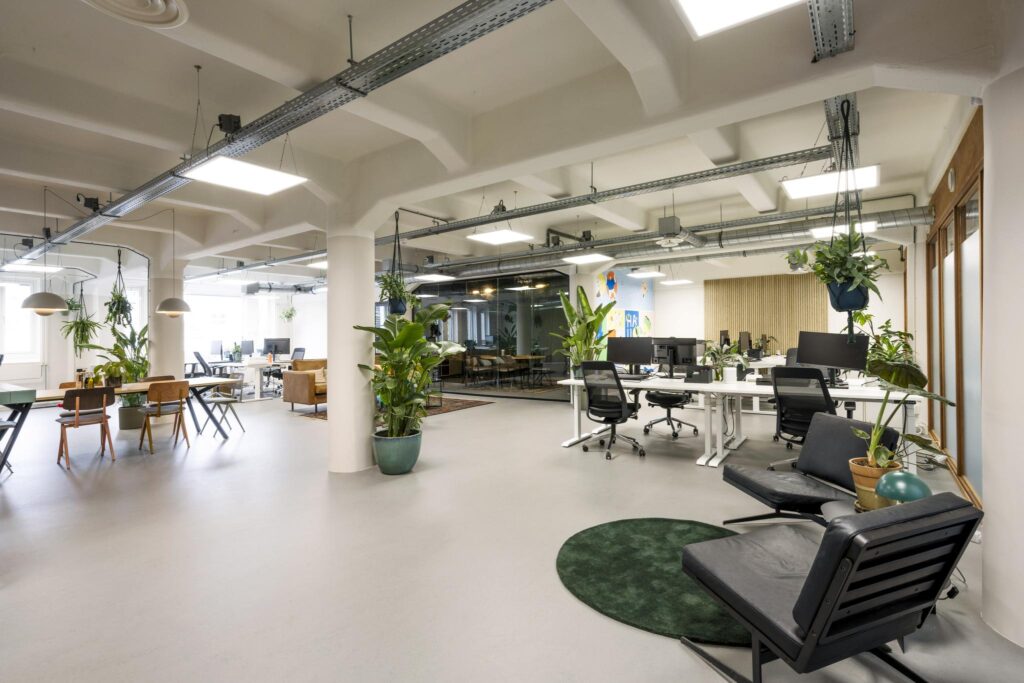 Modern open-plan office on Van Diemenstraat with desks, lounge areas, and indoor plants.